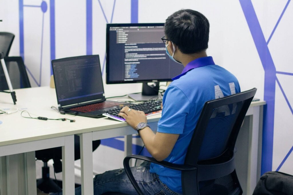 A developer or marketer working at a desk on a dual-monitor setup, likely optimizing a SaaS website or analyzing performance data with technical information visible on screen.